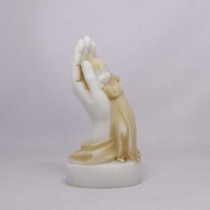 The statue of a girl is held by a hand in Patina color