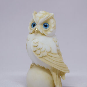 Owl sitting on a sphere in Patina color looking left